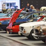 Wide interior view of a professional classic car showroom featuring a variety of vintage sports cars and luxury sedans.