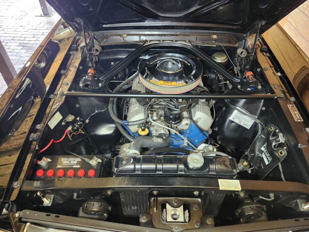 Overhead view of an open engine bay containing a highly detailed Ford 289 K-Code High Performance V8 engine.