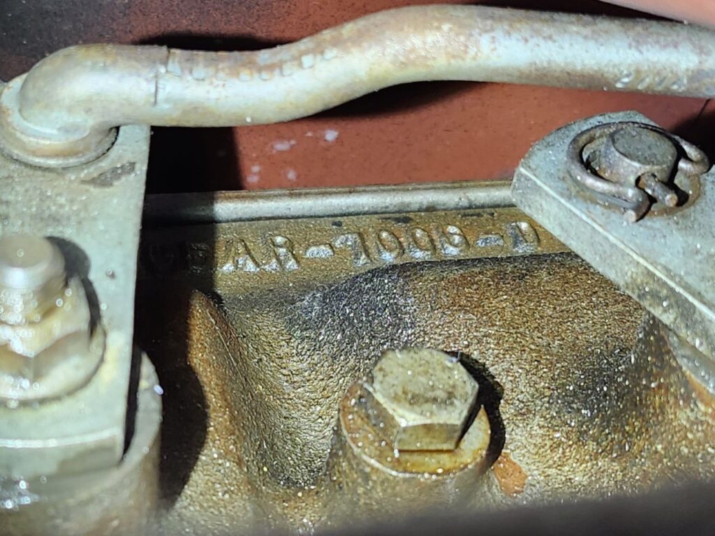 Macro photograph of the casting code "AR-7006-D" on a metal Ford Top Loader transmission case.