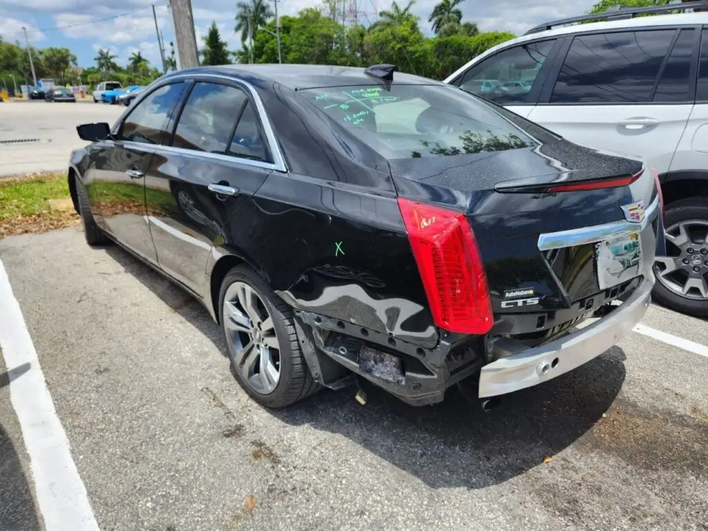 Evaluating rear-end bumper and quarter-panel damage on a black Cadillac CTS for a diminished value appraisal in Hialeah Florida.