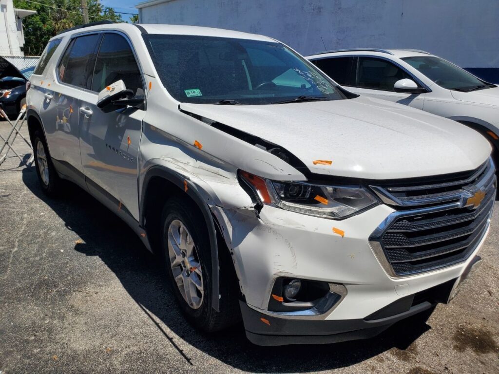 Assessing front-end and fender damage on a white Chevrolet Traverse as part of a professional diminished value appraisal Hollywood report.