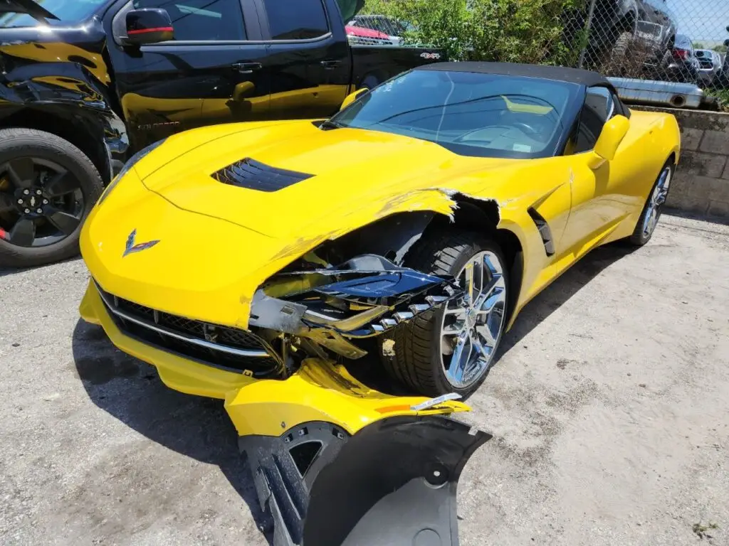 Evaluating severe front-end and fender damage on a yellow Chevrolet Corvette C7 for a professional diminished value appraisal Weston report.