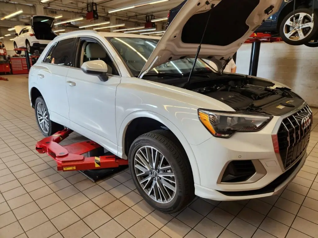 Professional under-the-hood and structural inspection of a white Audi Q3 for a diminished value appraisal in Coconut Creek Florida.