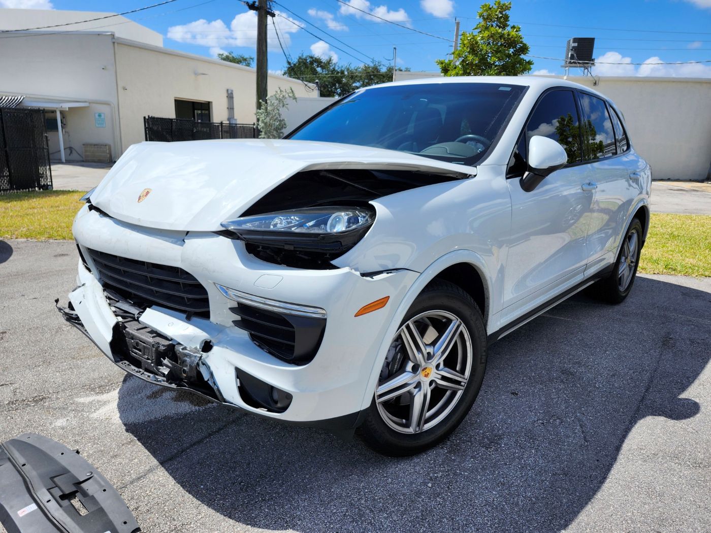 Evaluating significant front-end collision impact on a white Porsche Cayenne for a diminished value appraisal in Coconut Creek.