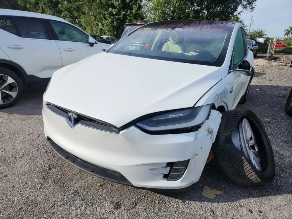 Documenting significant front-end collision and suspension damage on a white Tesla Model X for a diminished value appraisal in Coral Springs.