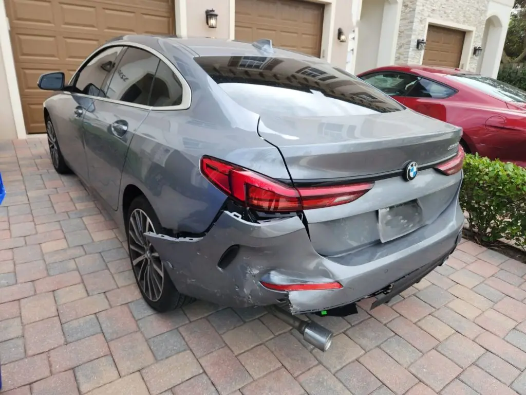Assessing rear-end bumper and quarter-panel damage on a grey 2024 BMW 228i Gran Coupe for a diminished value appraisal in Deerfield Beach Florida.