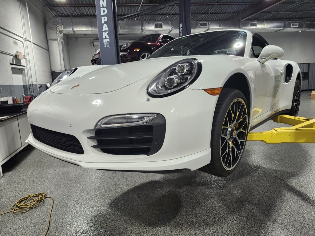 Undercarriage inspection of a white Porsche 911 during a diminished value appraisal in Delray Beach to evaluate market loss after repairs.