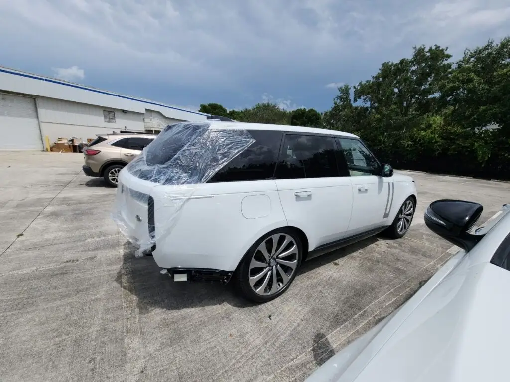 Assessing rear-end structural damage on a white 2023 Land Rover Range Rover for a diminished value appraisal in Miami Gardens Florida.