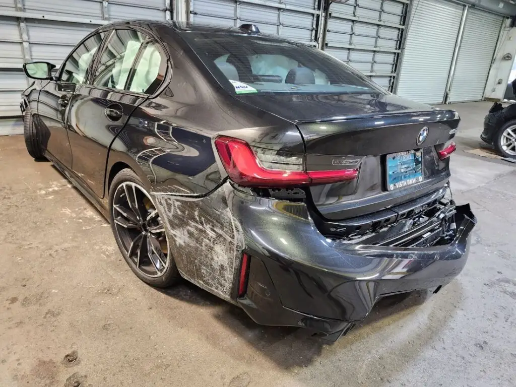 Assessing rear-end structural damage on a black 2024 BMW M340i for a diminished value appraisal in Pompano Beach Florida.