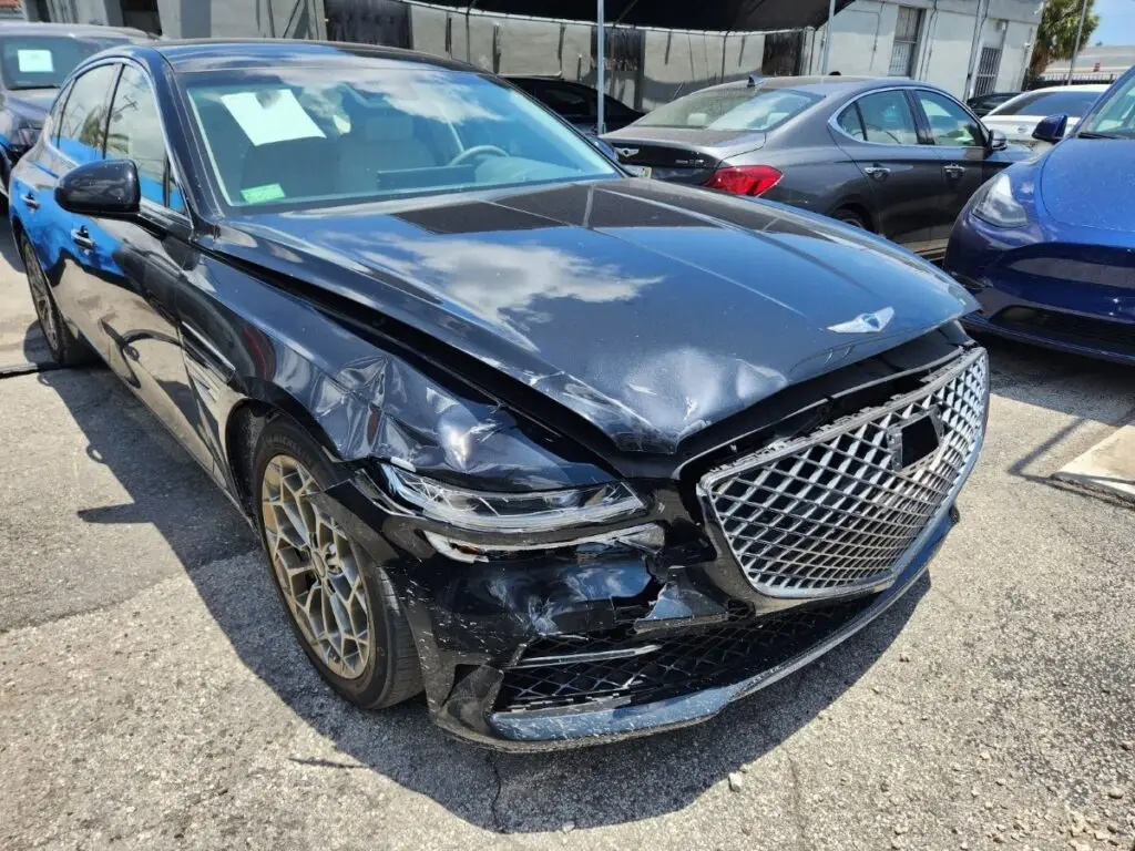 Assessing front-end and headlight damage on a black Genesis G80 as part of a professional diminished value appraisal in Homestead Florida.