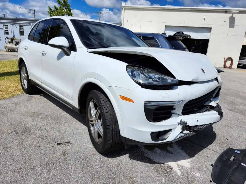 Evaluating severe front-end collision impact on a white Porsche Cayenne for a certified diminished value appraisal West Palm Beach Florida.