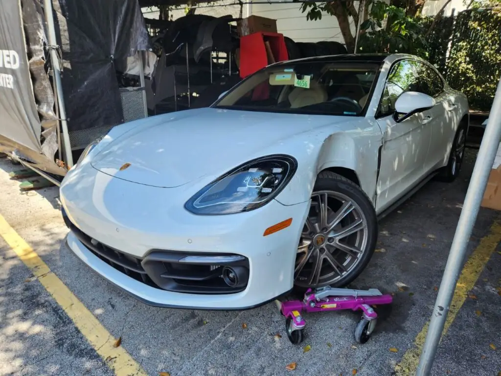Evaluating front-end and fender impact on a white Porsche Panamera as part of a diminished value appraisal in Jupiter Florida.