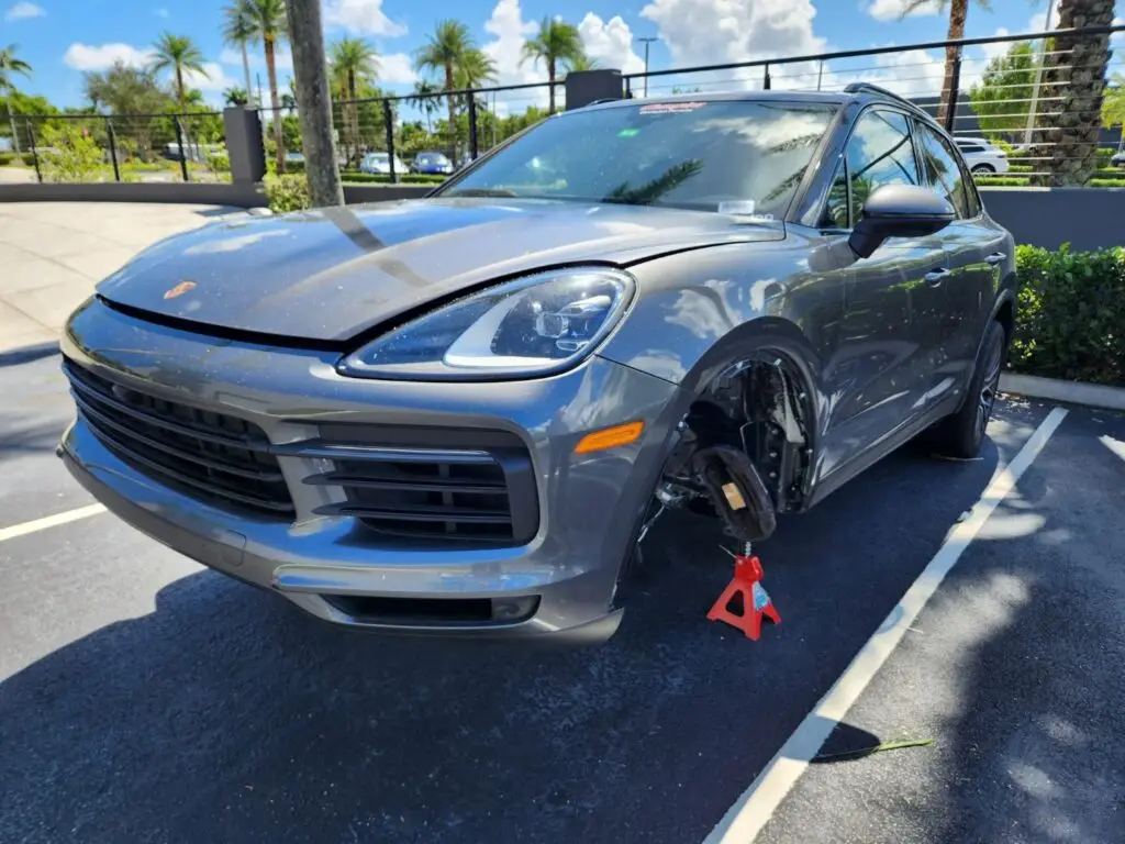 Front-end mechanical and suspension inspection of a grey Porsche Cayenne on a jack stand for a diminished value appraisal Lake Worth Florida.