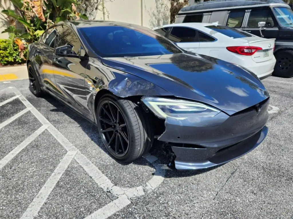 Technical inspection of front-end and fender damage on a dark grey Tesla Model S for an independent diminished value appraisal in Wellington.