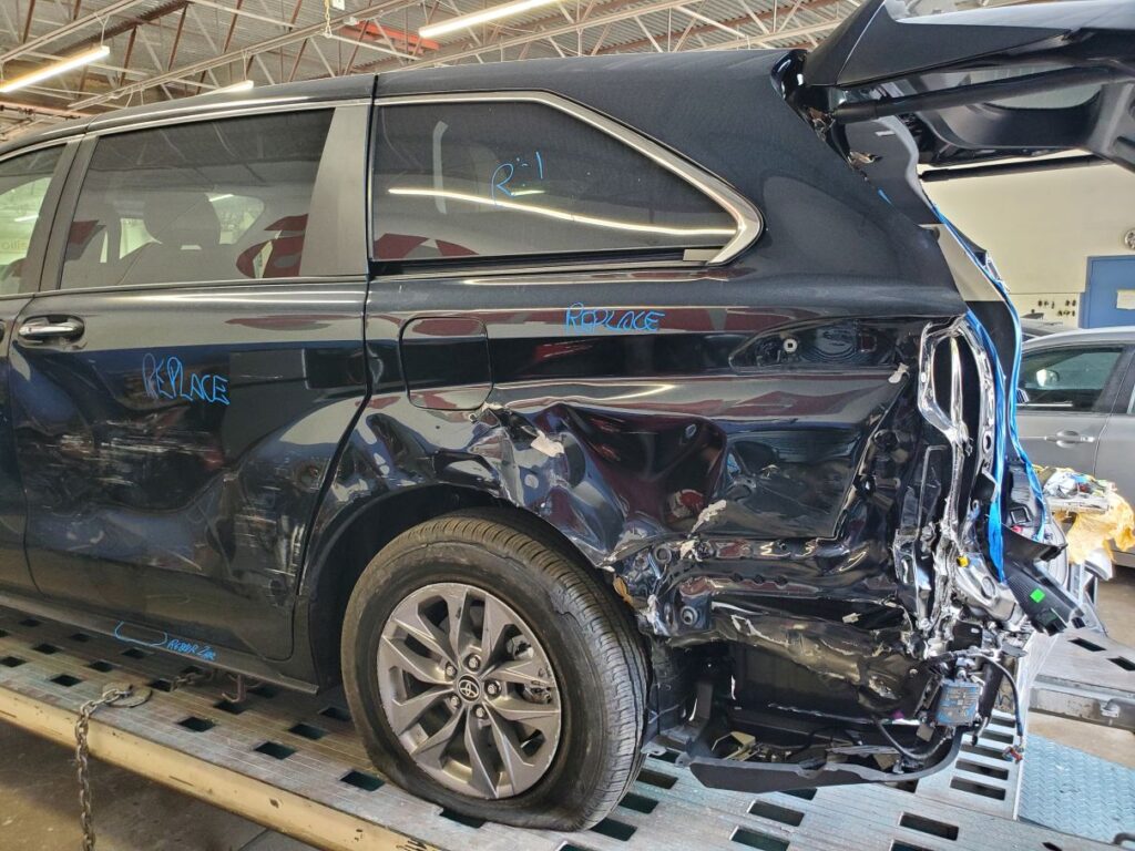 Toyota Sienna with severe rear-quarter panel and structural pillar damage on a frame rack, illustrating major accident depreciation in Coconut Creek.