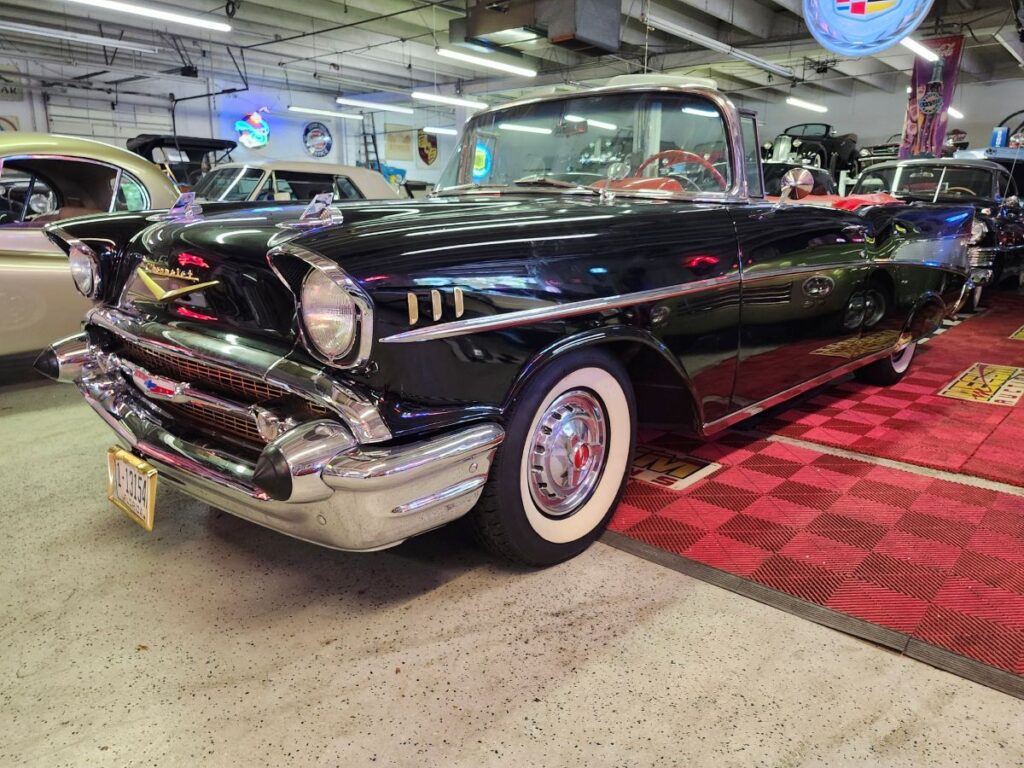 Restored black 1957 Chevrolet Bel Air with whitewall tires displayed in classic car collection showroom