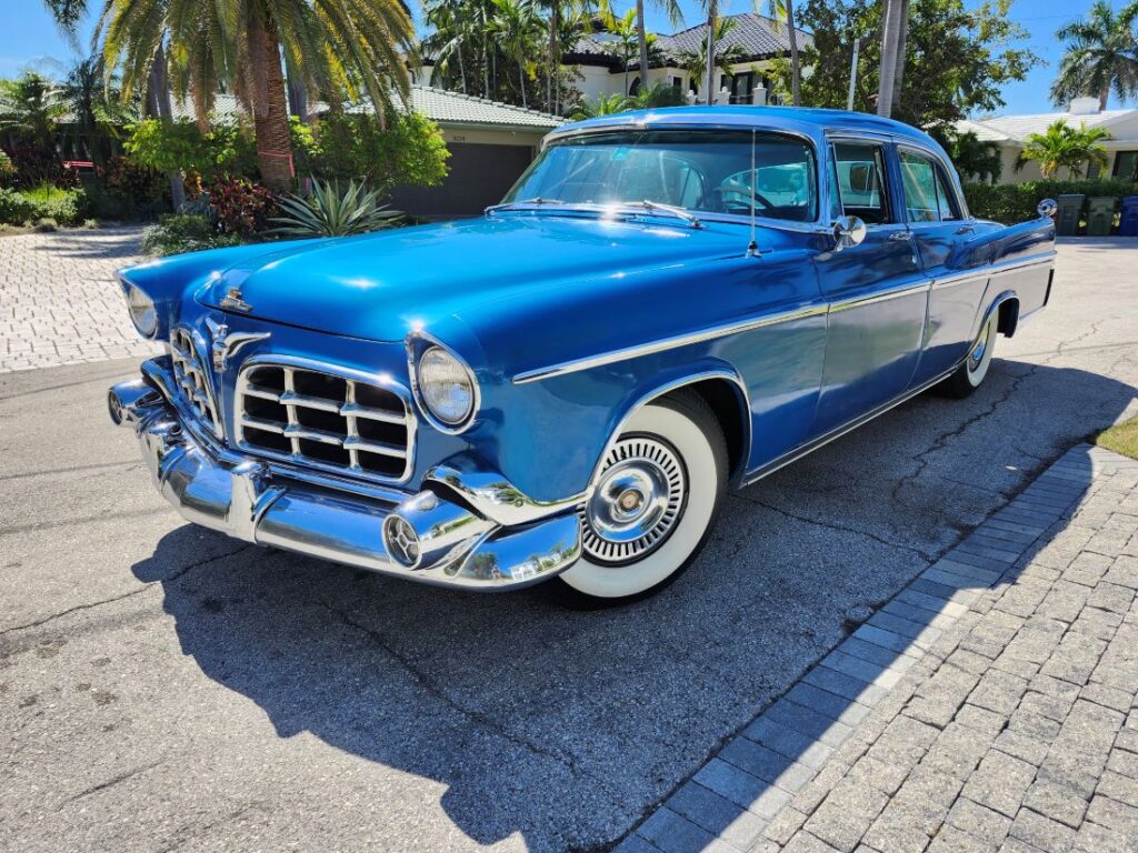 1956 Imperial Crown classic car in blue with chrome grille and whitewall tires parked in South Florida driveway