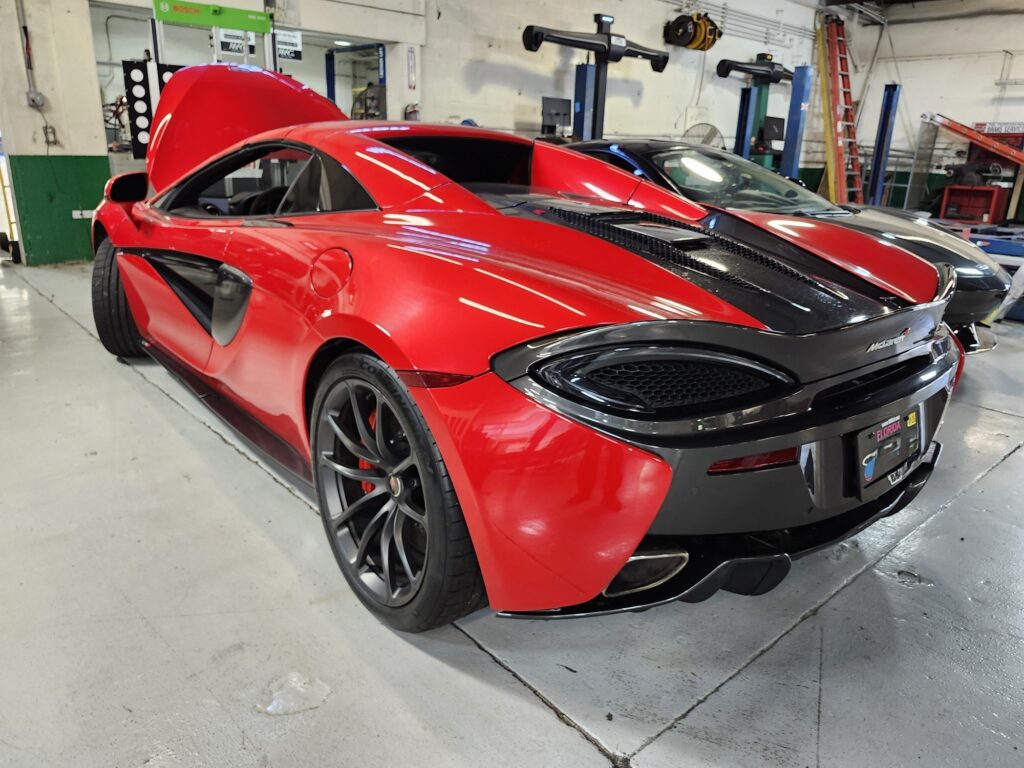 Red 2018 McLaren 570S coupe with hood open at rear-engine inspection during exotic vehicle diminished value appraisal