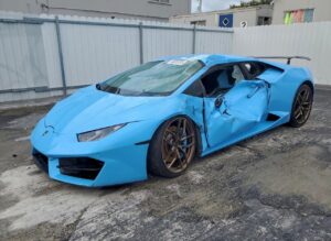 Blue 2016 Lamborghini Huracan supercar with severe driver side collision damage and shattered windshield assessed for total loss appraisal in Miami