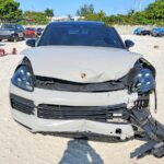 Porsche Cayenne SUV with severe front-end collision damage and detached bumper for total loss appraisal in Orlando