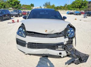 Porsche Cayenne SUV with severe front-end collision damage and detached bumper for total loss appraisal in Orlando