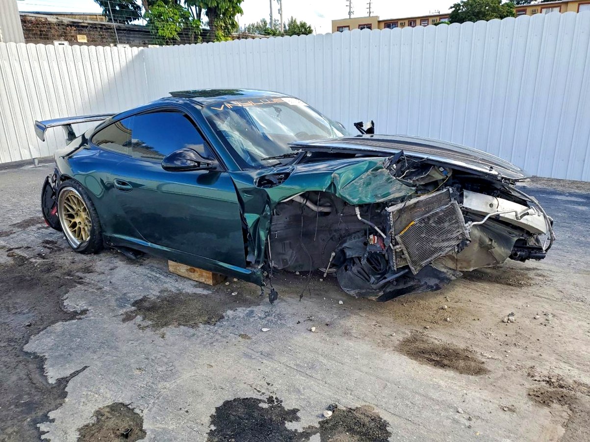 2012 Porsche 911 coupe with catastrophic front-end collision damage exposing engine components in Coral Gables for total loss appraisal