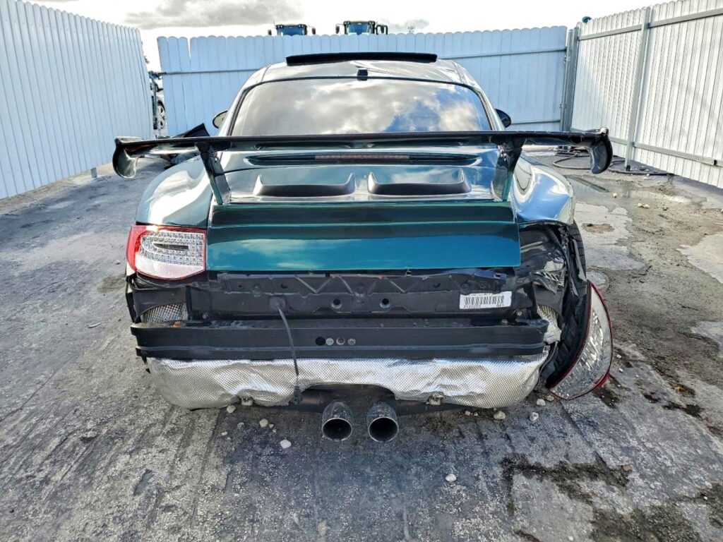 Rear view of Porsche 911 with rear bumper damage and large spoiler, assessed for total loss appraisal in Coral Gables, Florida