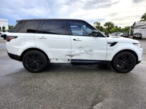 Range Rover Sport with deep door panel damage and scraping, evaluated for total loss appraisal in Jupiter, Florida