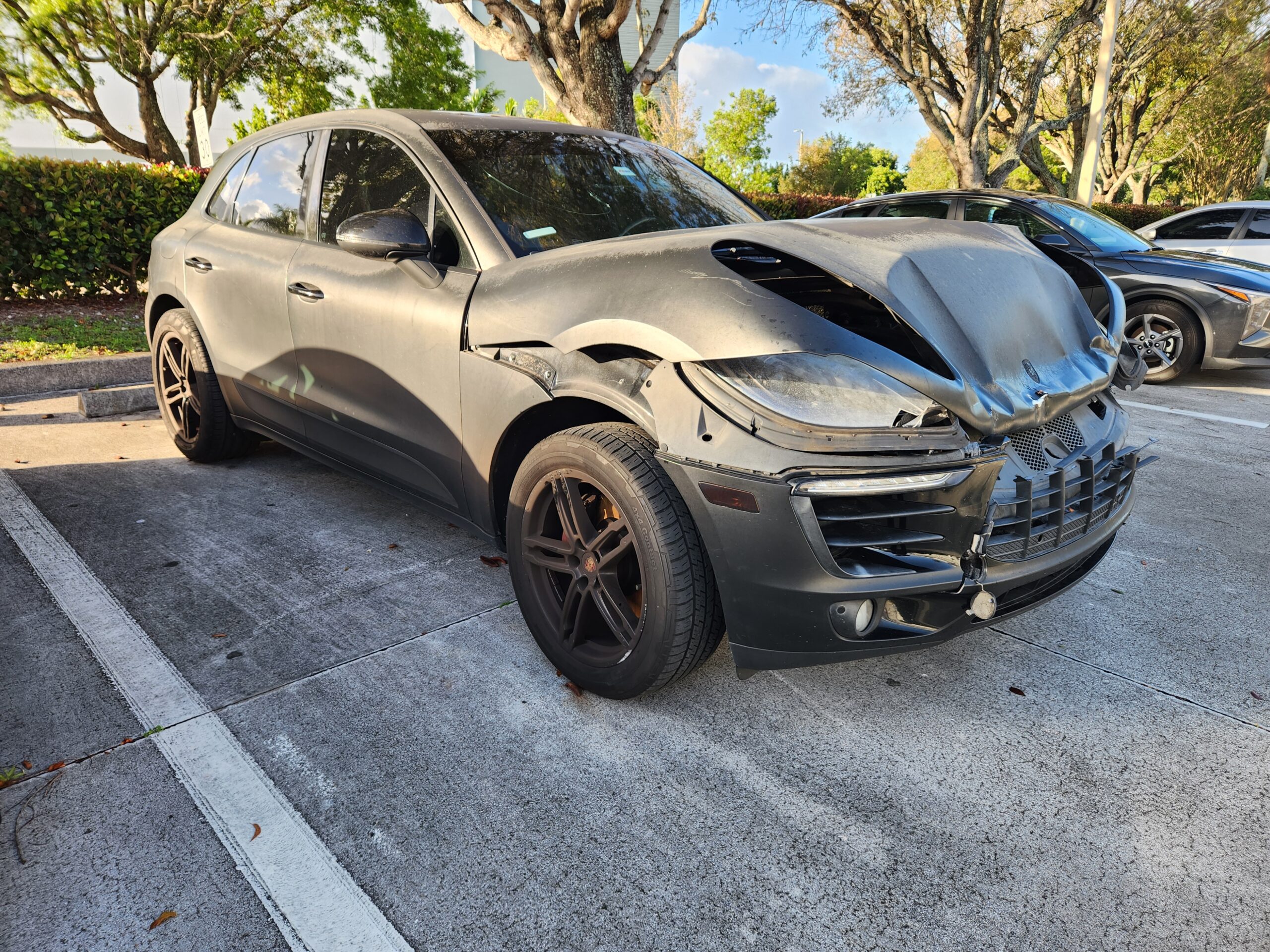 Porsche Macan with severe front-end collision damage and crumpled hood assessed for total loss appraisal in Margate Florida