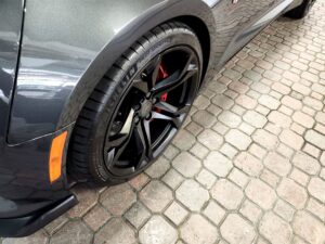 Close-up of Chevrolet Camaro wheel and red brake caliper during total loss appraisal in Pompano Beach, Florida