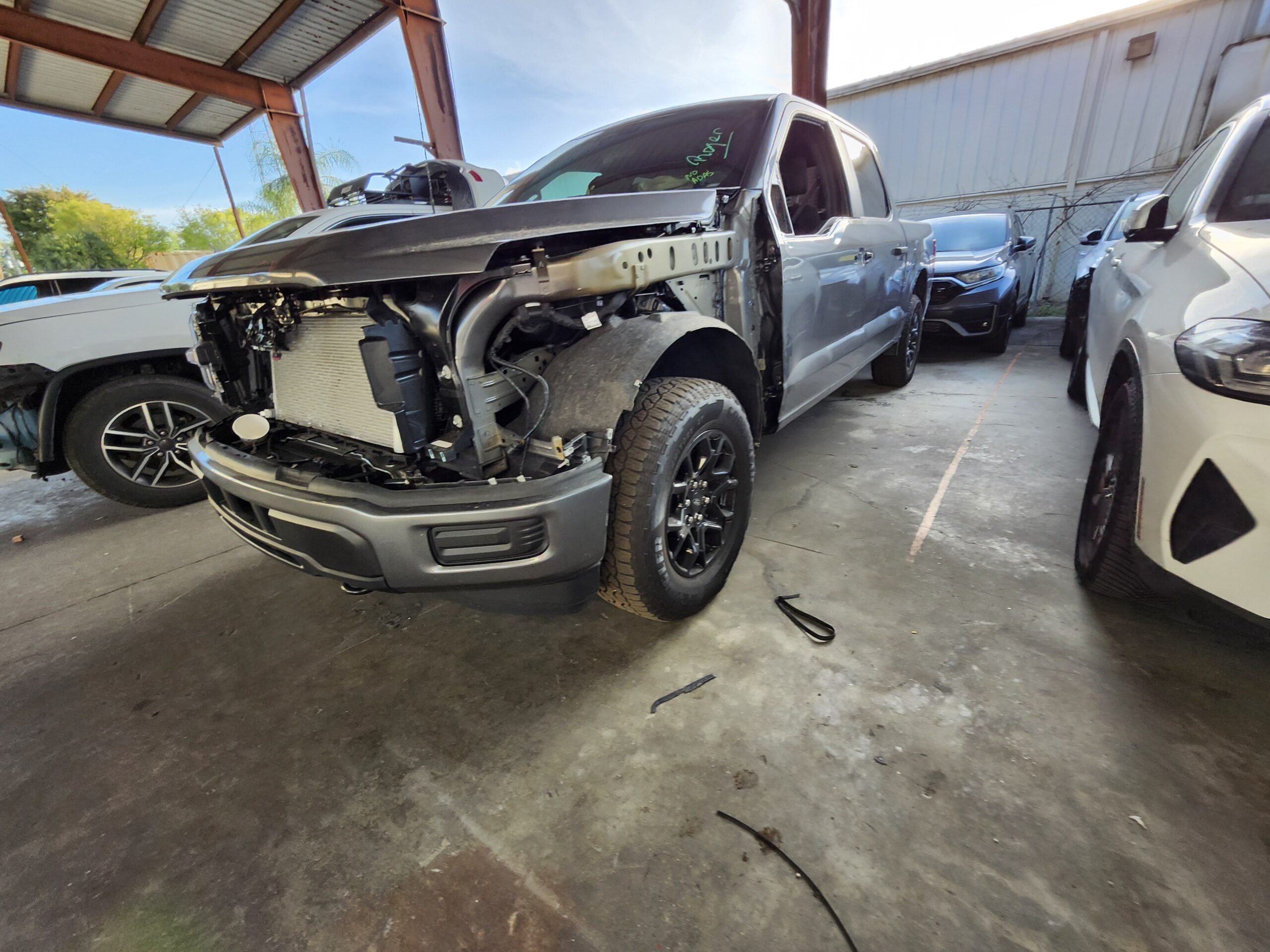 Ford F-150 truck with catastrophic front-end collision damage exposing engine bay assessed for total loss appraisal in Royal Palm Beach Florida