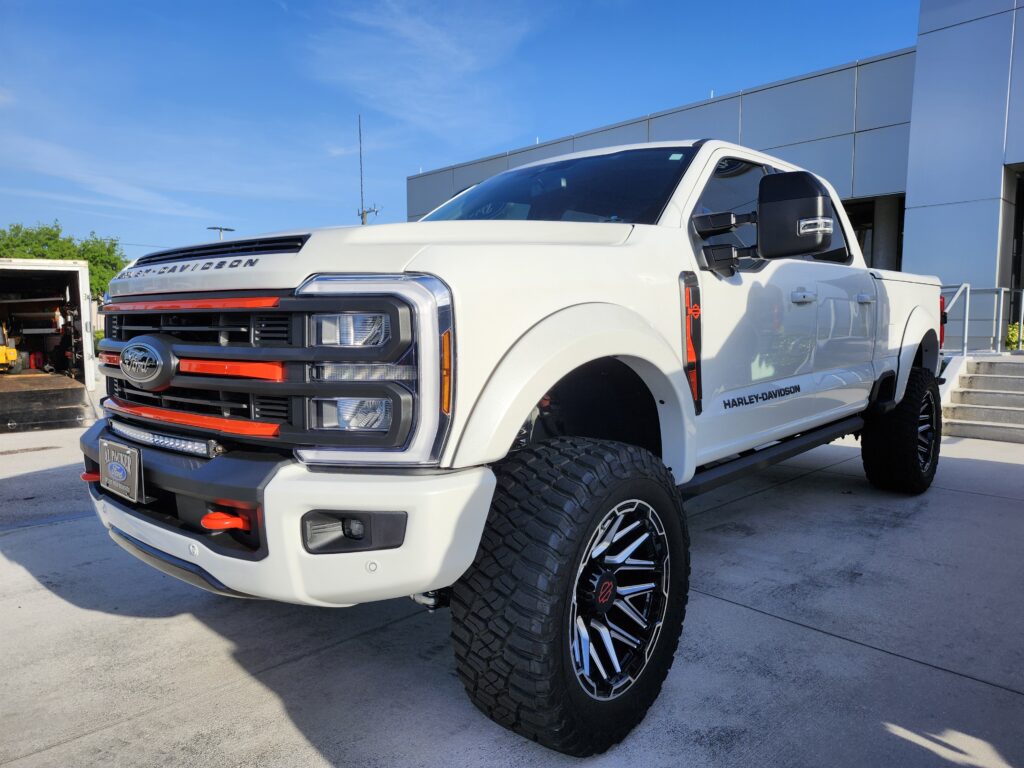 White Ford F-250 Harley-Davidson edition lifted truck with custom off-road wheels and orange accent grille photographed in Royal Palm Beach Florida for vehicle appraisal