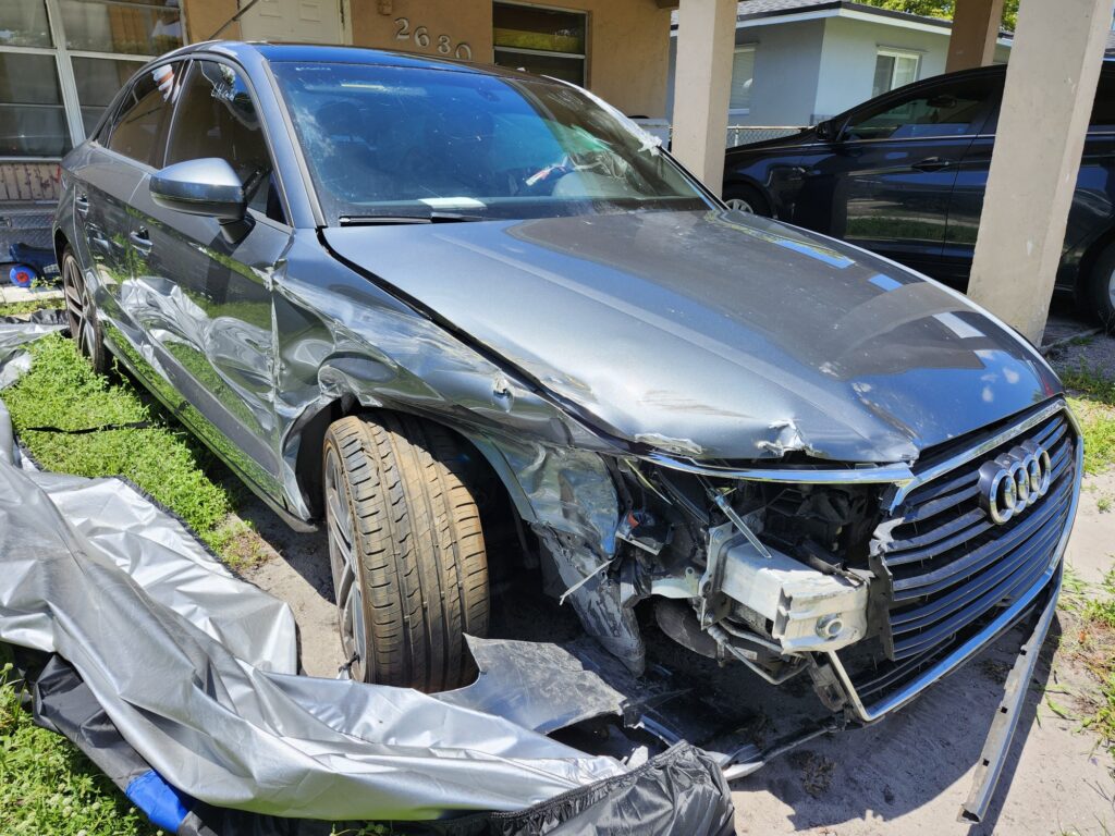 Gray Audi A3 sedan with severe front-end collision damage assessed for a total loss appraisal in Fort Lauderdale, Florida